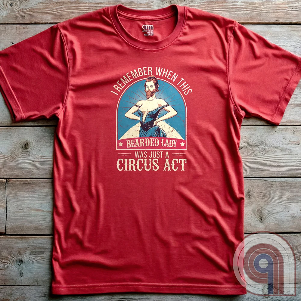 Step right up and witness the absurdity of modern times with this Bearded Lady Circus Act Freak Show Tee! Featuring a vintage sideshow design, this satirical shirt recalls an era when freak shows were confined to the circus tent—not celebrated in mainstream culture. Once a novelty act, now an everyday spectacle, this retro-inspired tee pokes fun at the bizarre shift in societal norms. Perfect for conservatives, free-thinkers, and those who refuse to accept forced narratives. Wear it loud! Color- Red2