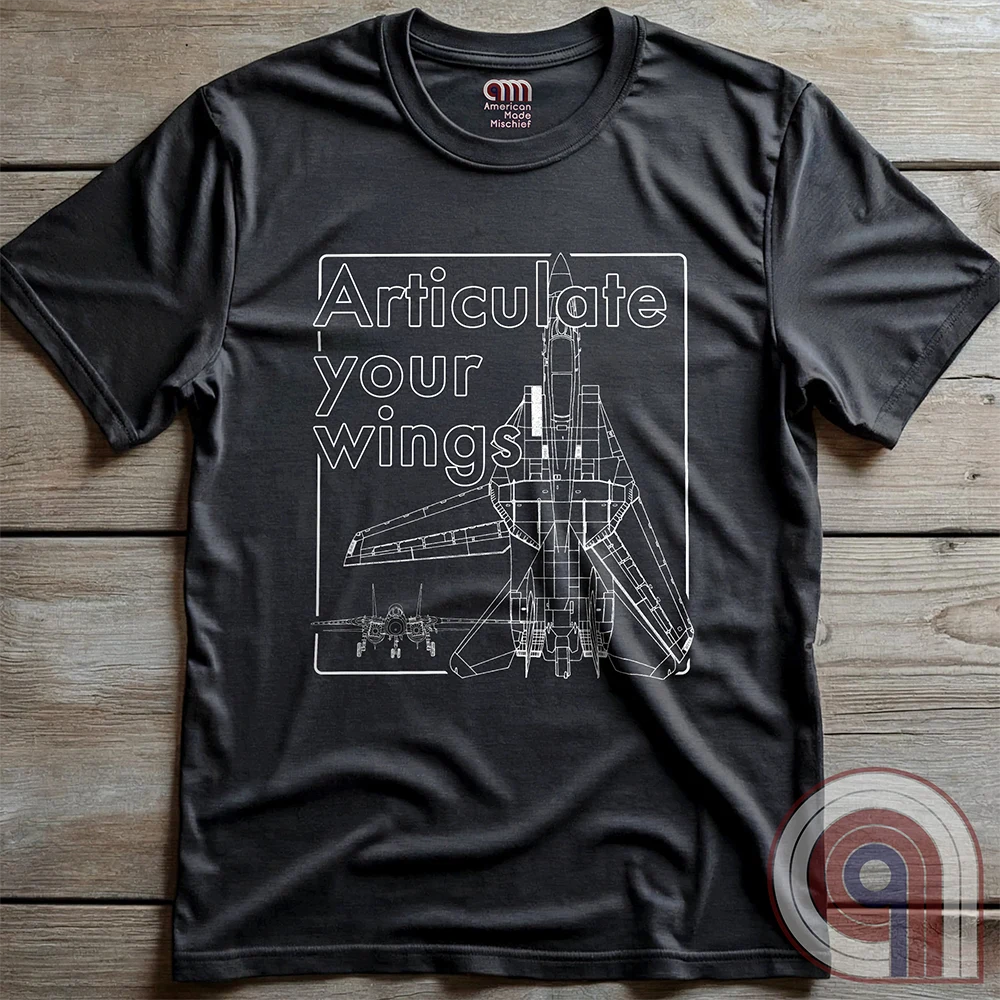 Charcoal T-shirt shown from above on wooden boards, with an F-14 fighter-jet schematic filling a fine white rectangular frame beside outlined “Articulate your wings!” lettering.