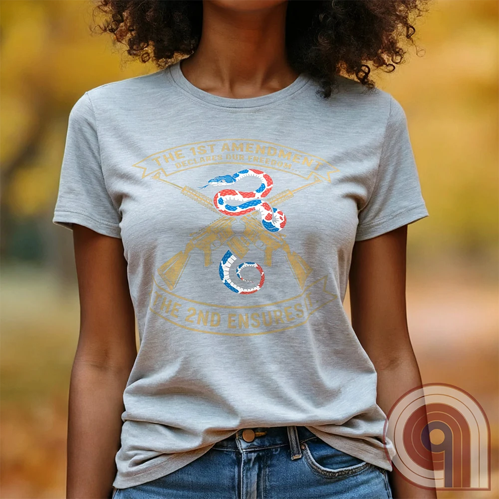 Show your commitment to the 1st & 2nd Amendments with this bold patriotic t-shirt. A fun 1A & 2A Tee featuring a red, white, & blue rattlesnake coiled around crossed rifles, this design represents free speech, gun rights, & resistance to tyranny. Perfect for Second Amendment supporters, constitutional patriots, & defenders of liberty. Whether you're standing against censorship or advocating for self-defense, this statement honors America’s founding principles and those who fight to protect them. Color: Ash