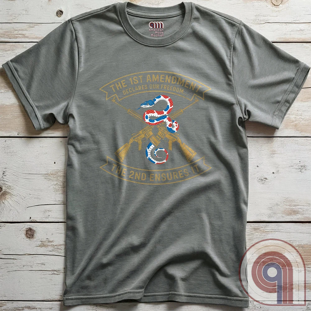 Show your commitment to the 1st & 2nd Amendments with this bold patriotic t-shirt. A fun 1A & 2A Tee featuring a red, white, & blue rattlesnake coiled around crossed rifles, this design represents free speech, gun rights, & resistance to tyranny. Perfect for Second Amendment supporters, constitutional patriots, & defenders of liberty. Whether you're standing against censorship or advocating for self-defense, this statement honors America’s founding principles and those who fight to protect them. Color: Grey