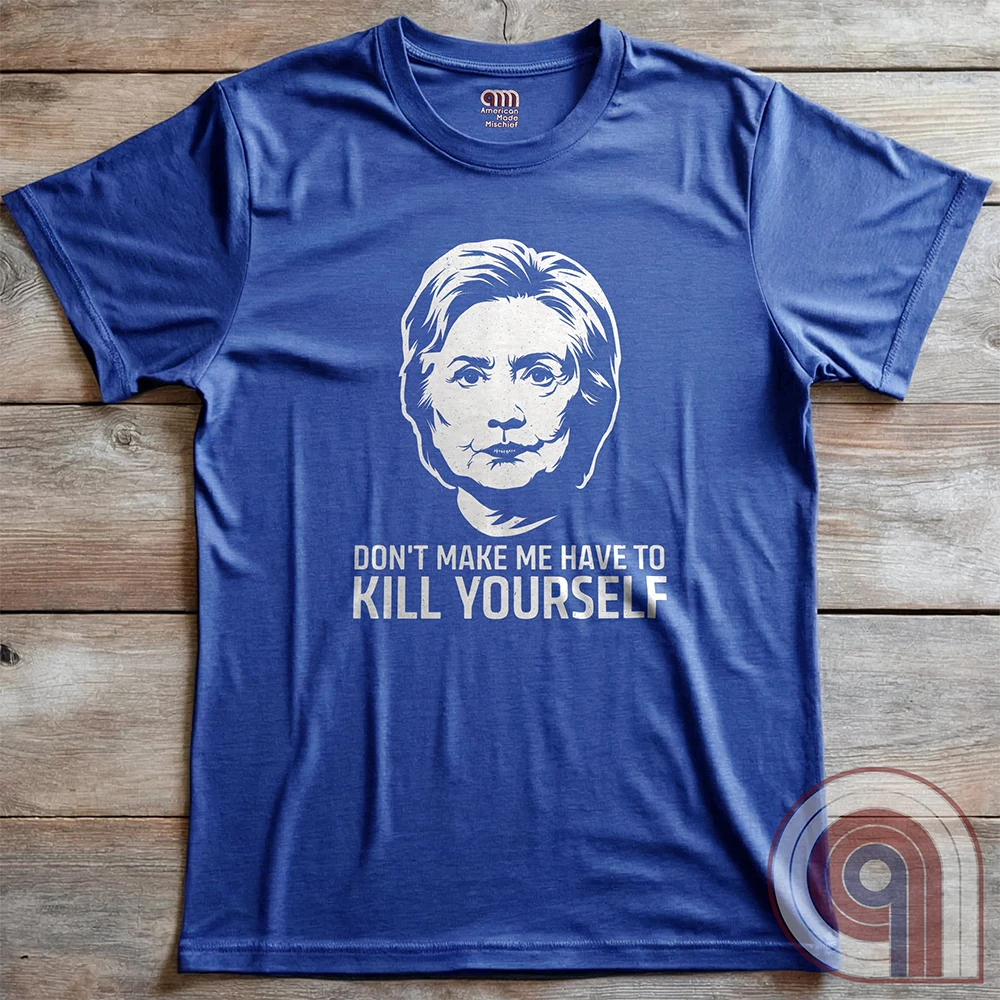 Heather blue tee laid flat on wooden boards, with a white stencil-like portrait of Hillary Clinton and the ominous satirical words “DON'T MAKE ME HAVE TO KILL YOURSELF”.