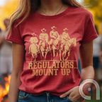 Ride high with the 'Regulators... Mount Up' t-shirt, a fearless call to action for patriots who stand for unity, resilience, & the preservation of American values. Inspired by frontier justice, this Western tee embodies the spirit of Texas Rangers, Border Patrol Agents, & Minute-Men. A tribute to law & order, standing strong, & defending freedom, it's perfect for those who believe in 2A, 1A, & American spirit. Whether you're a cowboy, prepper, or patriot, wear it with pride and ride for liberty. Red