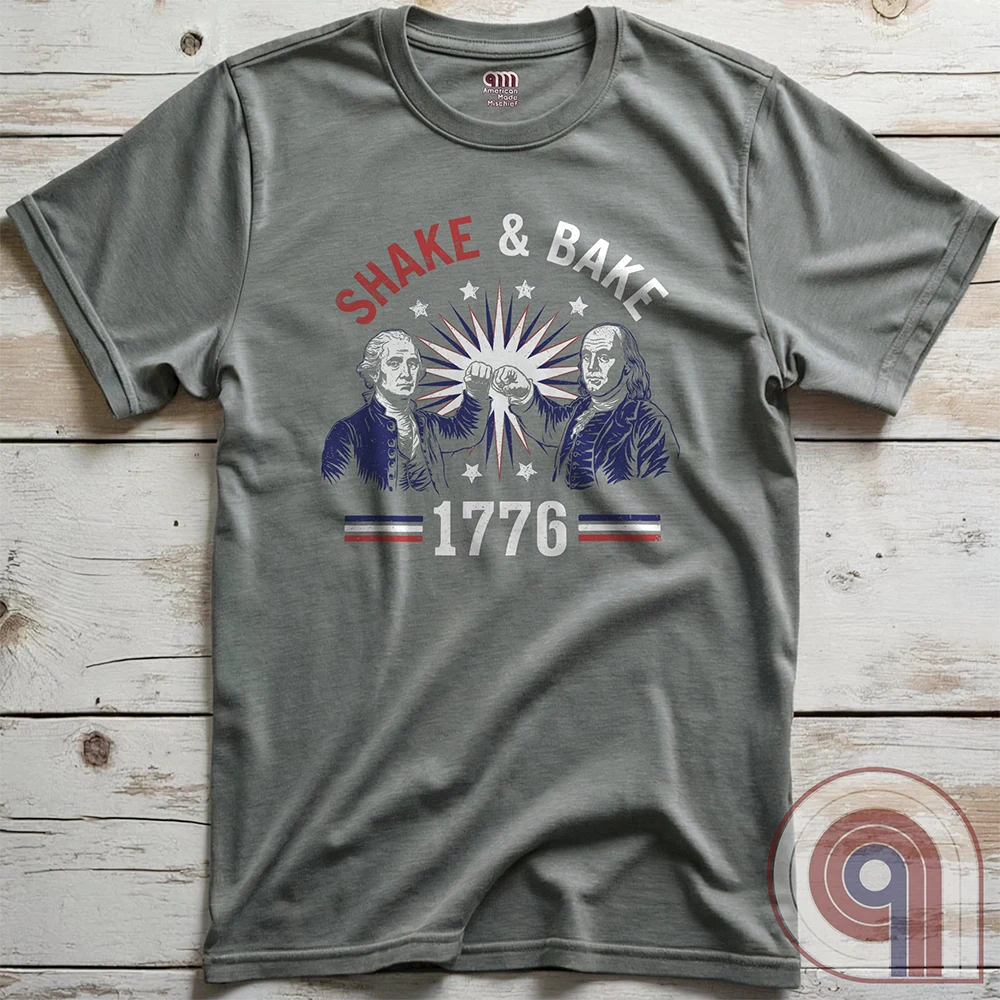 Revolution meets the racetrack with this Talladega Nights-inspired “Shake & Bake 1776” design, featuring George Washington and Benjamin Franklin throwing a victorious fist bump. A patriotic mashup of NASCAR culture and Founding Father grit, this tee celebrates American independence with speed, style, and historical swagger. Perfect for history buffs, liberty lovers, and anyone who believes in freedom, fast cars, and finishing first—because if you ain’t first, you’re last! Comedy Parody Tee. Color-Grey