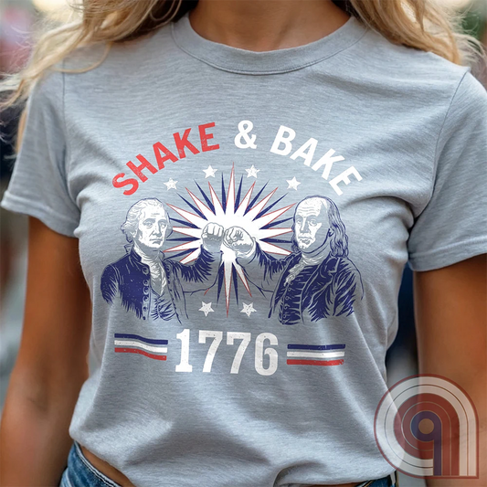Revolution meets the racetrack with this Talladega Nights-inspired “Shake & Bake 1776” design, featuring George Washington and Benjamin Franklin throwing a victorious fist bump. A patriotic mashup of NASCAR culture and Founding Father grit, this tee celebrates American independence with speed, style, and historical swagger. Perfect for history buffs, liberty lovers, and anyone who believes in freedom, fast cars, and finishing first—because if you ain’t first, you’re last! Comedy Parody Tee. Color- Ash