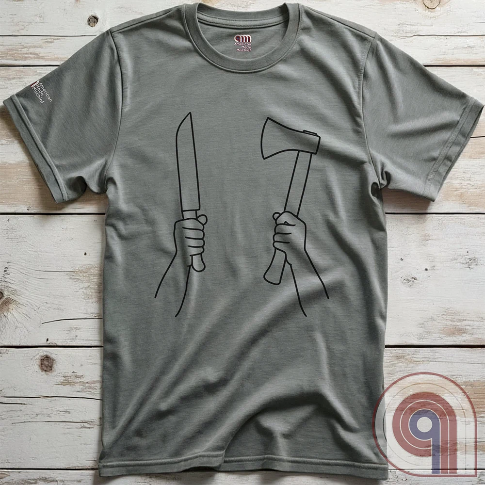 Heather gray T-shirt displayed flat on wooden boards, its black line-art print depicting two hands raised with a blade and a small axe.