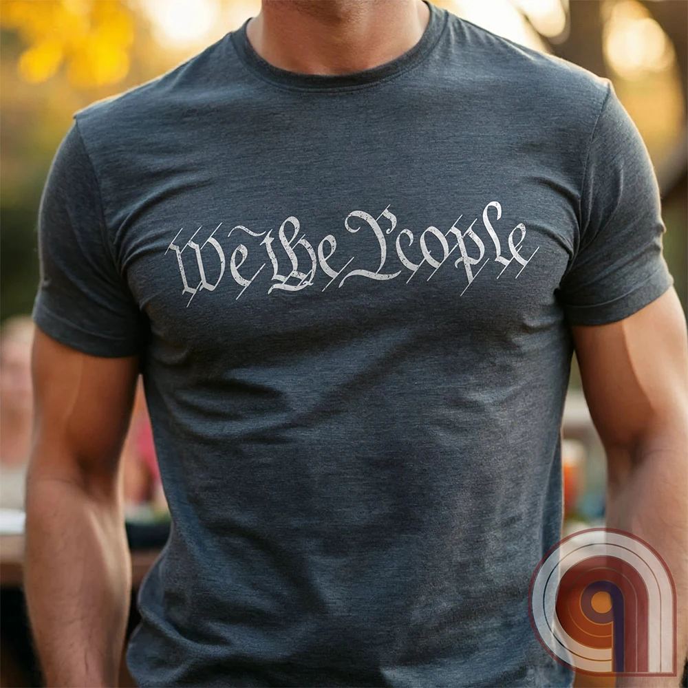 Charcoal T-shirt on a model, with just the words “We the People” across the chest in distressed, off-white Constitution-style calligraphy.