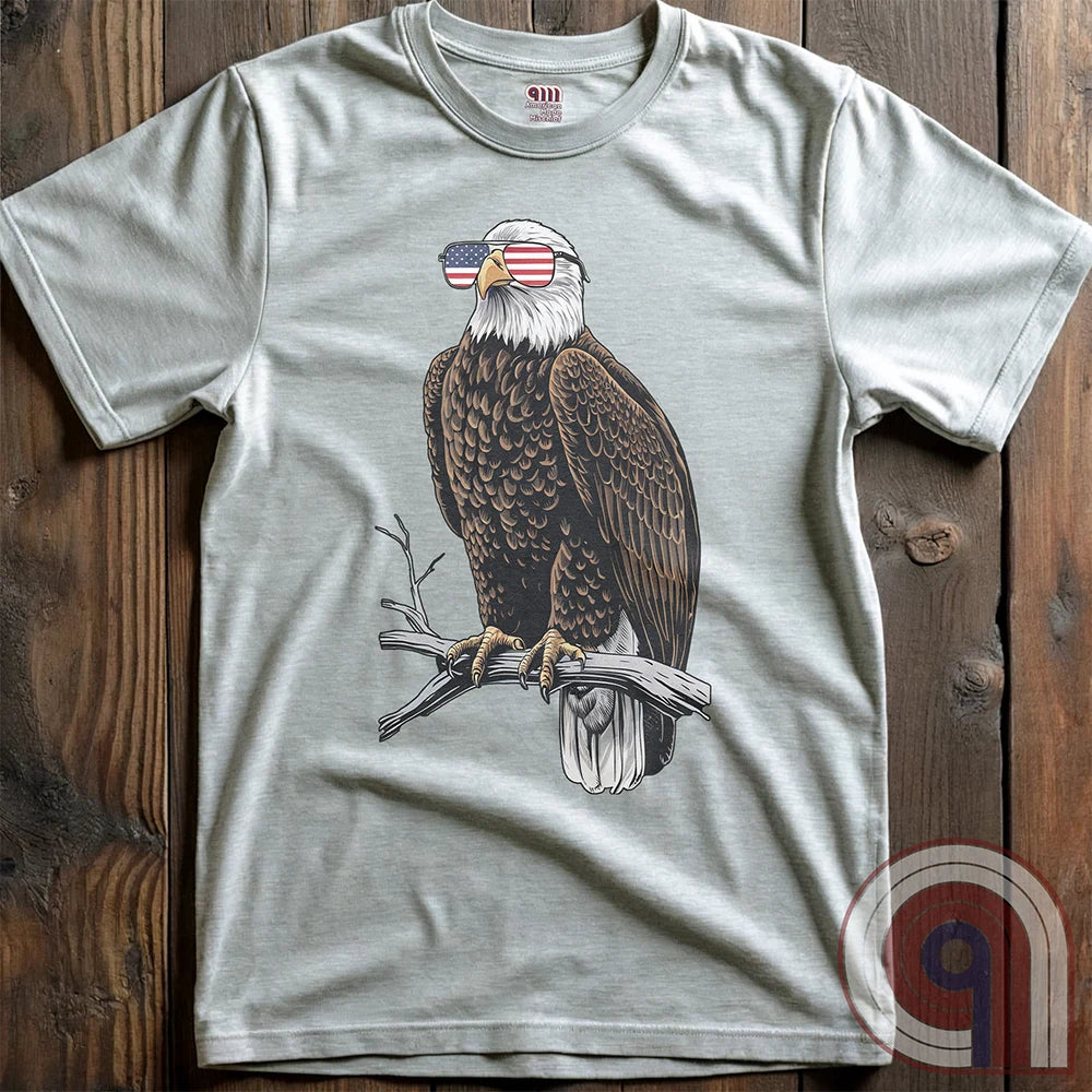 Declare your independence with this striking Pro USA t-shirt featuring America’s ultimate symbol of freedom—the bald eagle—sporting American flag sunglasses. It’s not just a patriotic tee—it’s a statement of strength, sovereignty, and pride. 
Bald eagle t-shirt;Patriotic eagle shirt;American flag sunglasses design;USA freedom shirt;Pro-America graphic tee;Unisex patriotic t-shirt;Eagle with American flag glasses shirt;Conservative values;July 4th eagle t-shirt;USA-made freedom apparel;MAGA;1776; - Ash