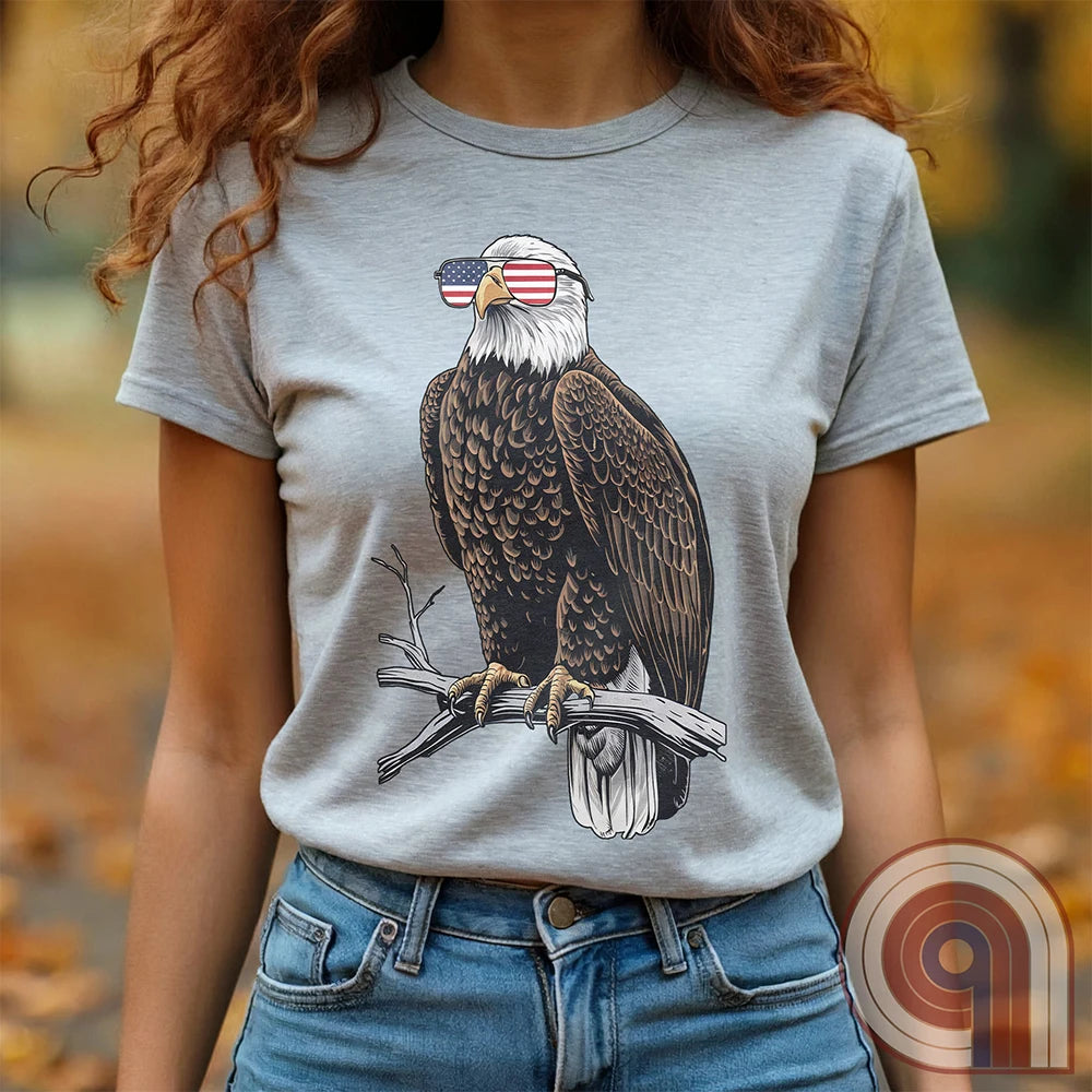 Declare your independence with this striking Pro USA t-shirt featuring America’s ultimate symbol of freedom—the bald eagle—sporting American flag sunglasses. It’s not just a patriotic tee—it’s a statement of strength, sovereignty, and pride. 
Bald eagle t-shirt;Patriotic eagle shirt;American flag sunglasses design;USA freedom shirt;Pro-America graphic tee;Unisex patriotic t-shirt;Eagle with American flag glasses shirt;Conservative values;July 4th eagle t-shirt;USA-made freedom apparel;MAGA;1776; - Ash