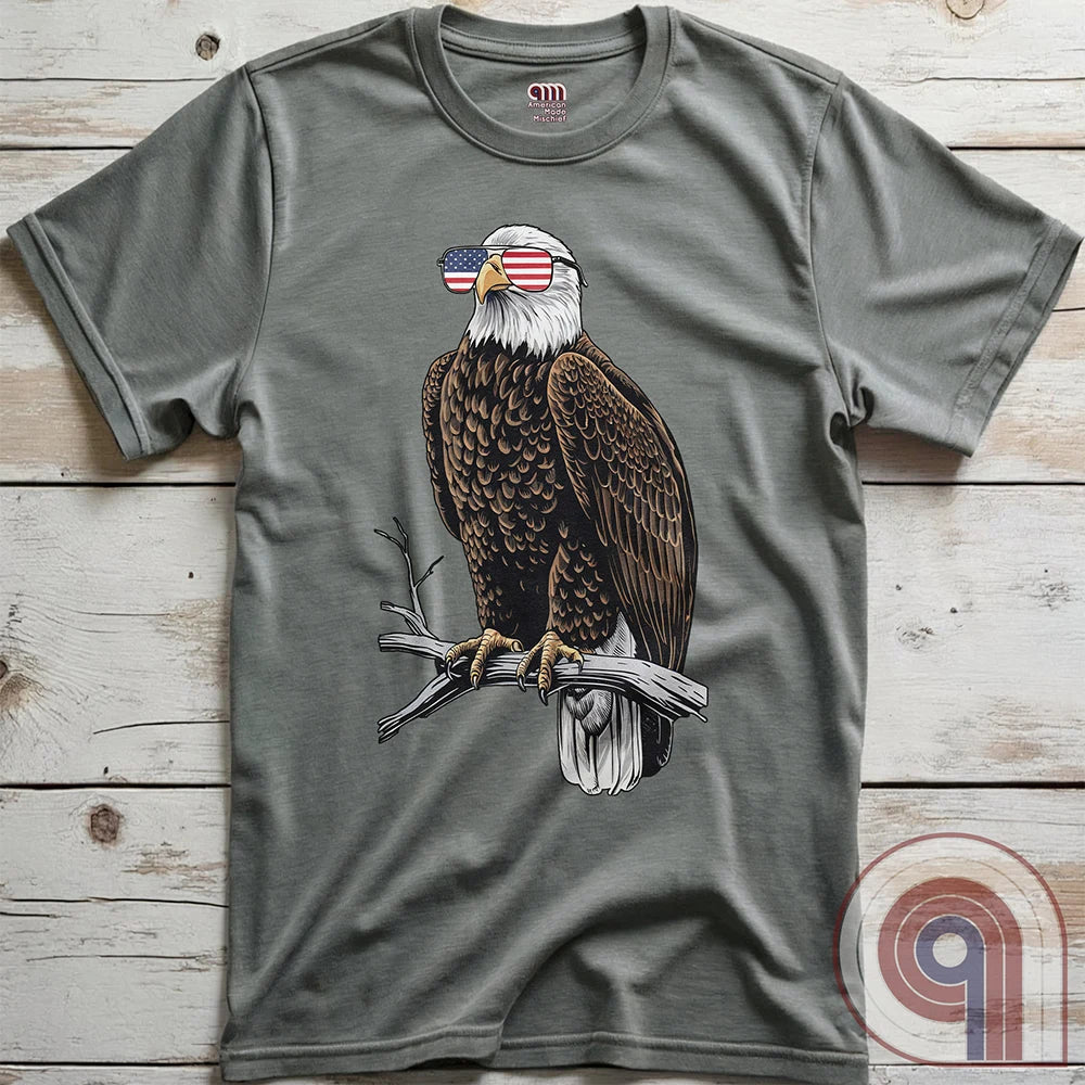 Declare your independence with this striking Pro USA t-shirt featuring America’s ultimate symbol of freedom—the bald eagle—sporting American flag sunglasses. It’s not just a patriotic tee—it’s a statement of strength, sovereignty, and pride. 
Bald eagle t-shirt;Patriotic eagle shirt;American flag sunglasses design;USA freedom shirt;Pro-America graphic tee;Unisex patriotic t-shirt;Eagle with American flag glasses shirt;Conservative values;July 4th eagle t-shirt;USA-made freedom apparel;MAGA;1776; - Grey