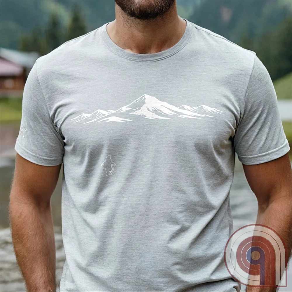 Minimalist inspirational t-shirt graphic showing a lone penguin walking away beneath a vast snow-covered mountain range, inspired by Werner Herzog’s wandering penguin documentary scene. This Tee evokes existential solitude, Faustian spirit, nihilism, faith, and quiet bravery, symbolizing the call to adventure, isolation, perseverance, philosophy, and the human search for meaning through nature, exploration, and understated surreal meme culture.
Ash