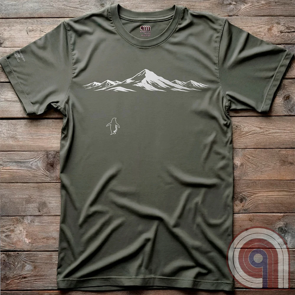 Minimalist inspirational t-shirt graphic showing a lone penguin walking away beneath a vast snow-covered mountain range, inspired by Werner Herzog’s wandering penguin documentary scene. This Tee evokes existential solitude, Faustian spirit, nihilism, faith, and quiet bravery, symbolizing the call to adventure, isolation, perseverance, philosophy, and the human search for meaning through nature, exploration, and understated surreal meme culture. Green