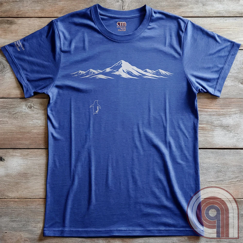 Minimalist inspirational t-shirt graphic showing a lone penguin walking away beneath a vast snow-covered mountain range, inspired by Werner Herzog’s wandering penguin documentary scene. This Tee evokes existential solitude, Faustian spirit, nihilism, faith, and quiet bravery, symbolizing the call to adventure, isolation, perseverance, philosophy, and the human search for meaning through nature, exploration, and understated surreal meme culture. 
Blue