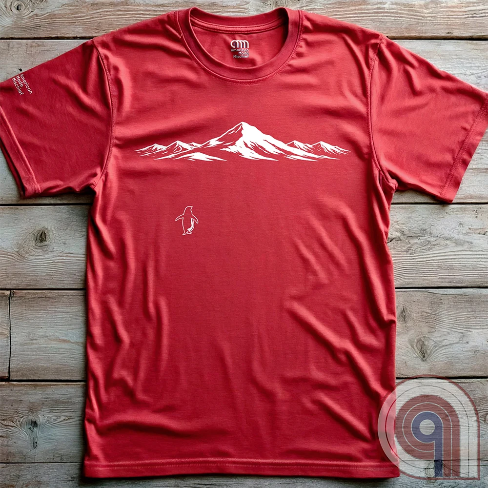 Minimalist inspirational T-shirt featuring a lone penguin walking away beneath a wide snow-covered mountain range. Inspired by Werner Herzog’s documentary scene of the wandering penguin, the design symbolizes existential solitude, nihilism, faith, and the call to adventure, blending philosophy, nature, and understated meme culture in a subtle, wearable graphic. Red
