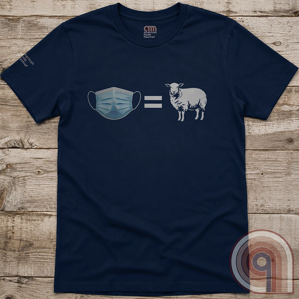 Navy tee laid flat on wood planks, printed with the compact blue-mask-equals-white-sheep comparison and no accompanying lettering.