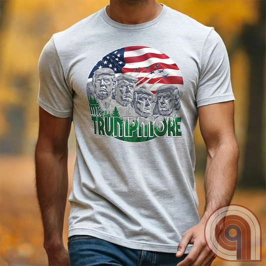 Mount Trumpmore stands as a bold symbol of American resilience, patriotism, and leadership. This striking t-shirt reimagines a national monument in the image of Donald Trump, embodying strength, defiance, & commitment to America first. Set against the stars & stripes, this shirt captures the grandeur of a historical moment & the glory of a triumphant return. For patriots who refuse to let America fade, this tee celebrates leadership and a vision of American greatness carved into history. Color- Ash1