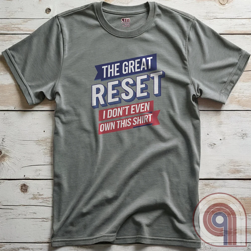 Heather grey Great Reset parody T-shirt displayed flat on wooden planks. Blue banners and oversized white type frame the punchline “I DON’T EVEN OWN THIS SHIRT” beneath “THE GREAT RESET”.